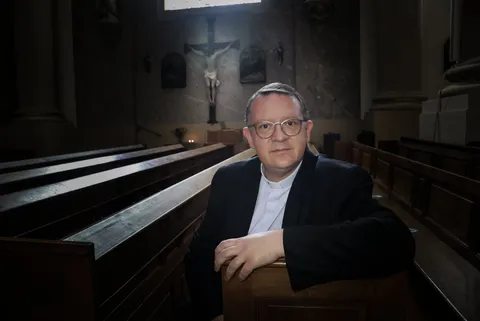 Le Père Stéphane Kamm, assis dans les bancs de son église