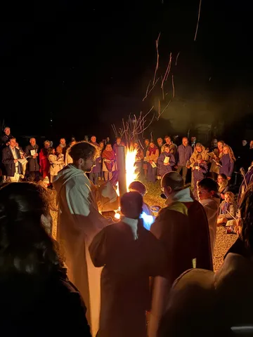 Une veillée de nuit à la lueur des bougies et d'un feu, devant l'assemblée rassemblée