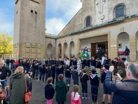 Un grand rassemblement de scouts devant une basilique, un jour d'automne